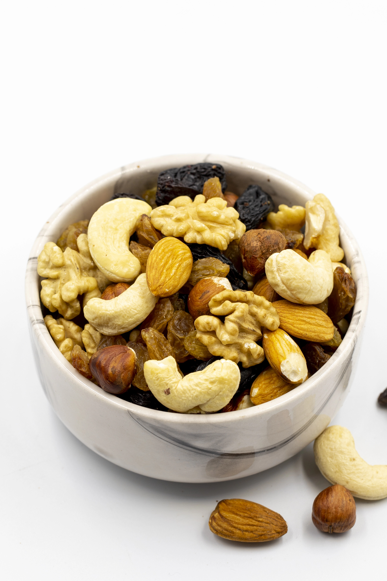 Mixed nuts and raisins in white bowl