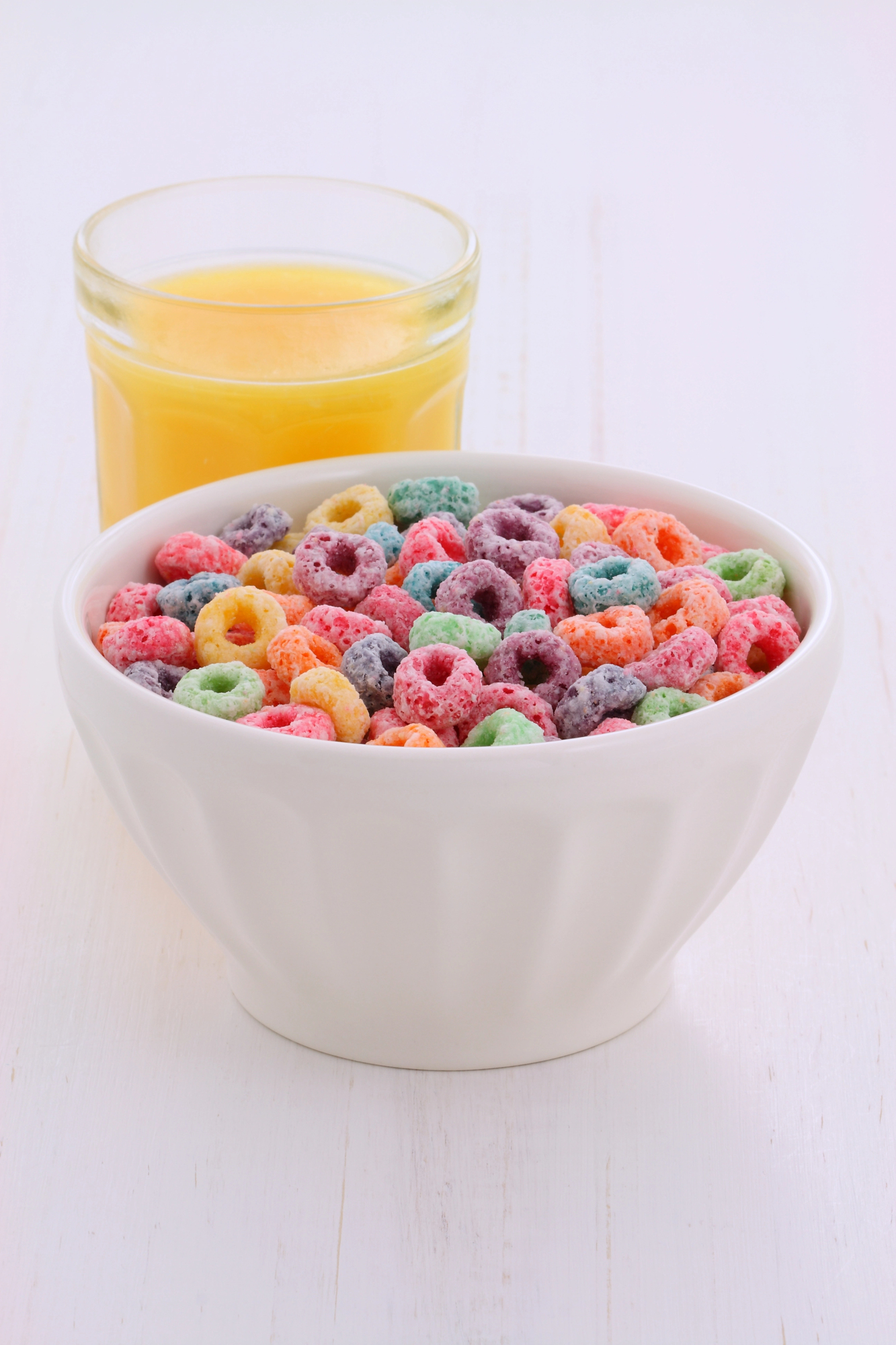 Colorful cereal loops in white bowl with juice