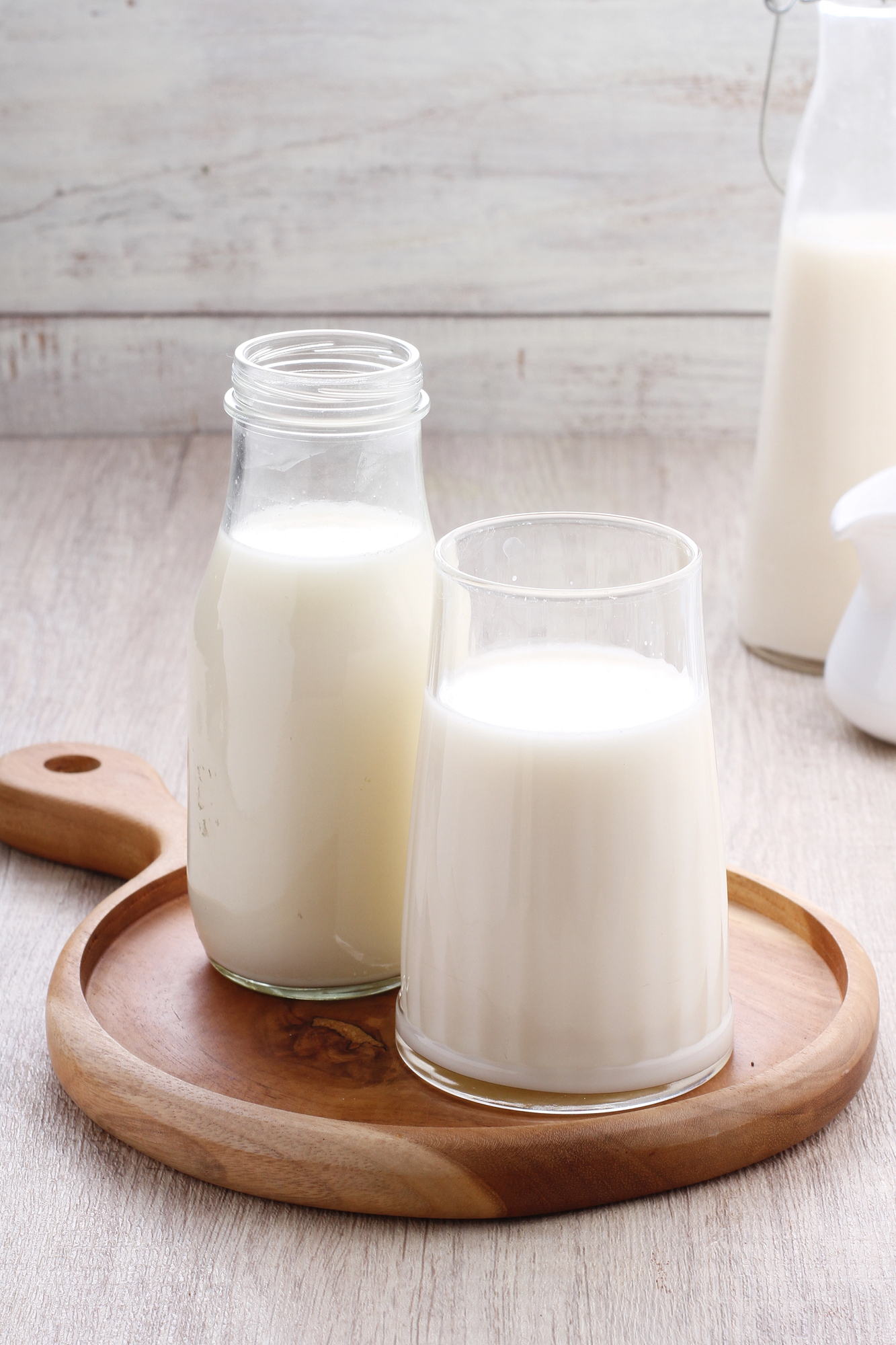 Glass and bottle of milk on wooden tray
