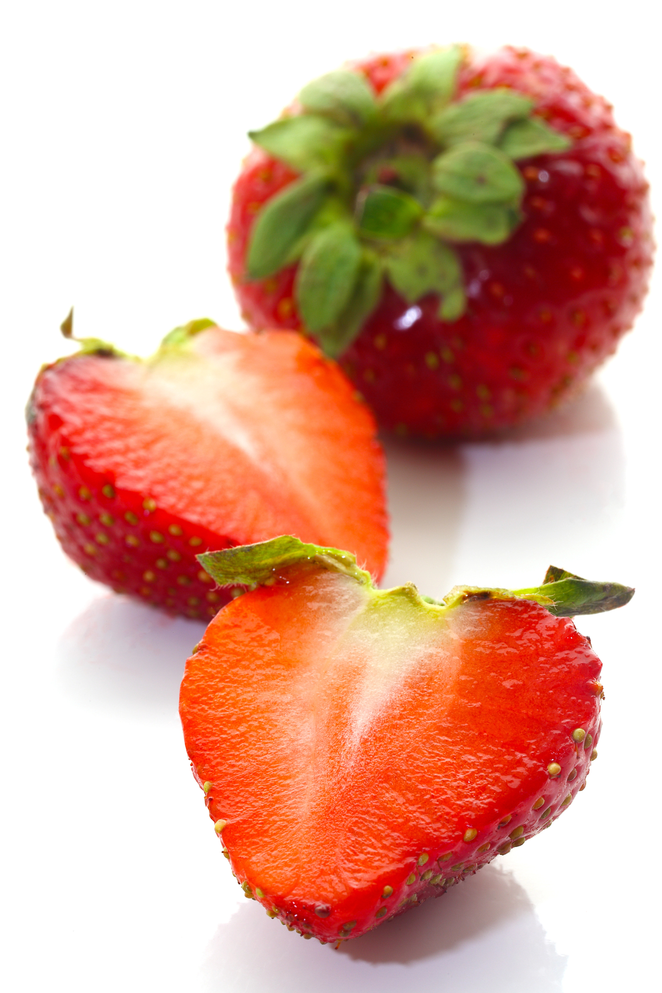 Two halved strawberries and one whole strawberry