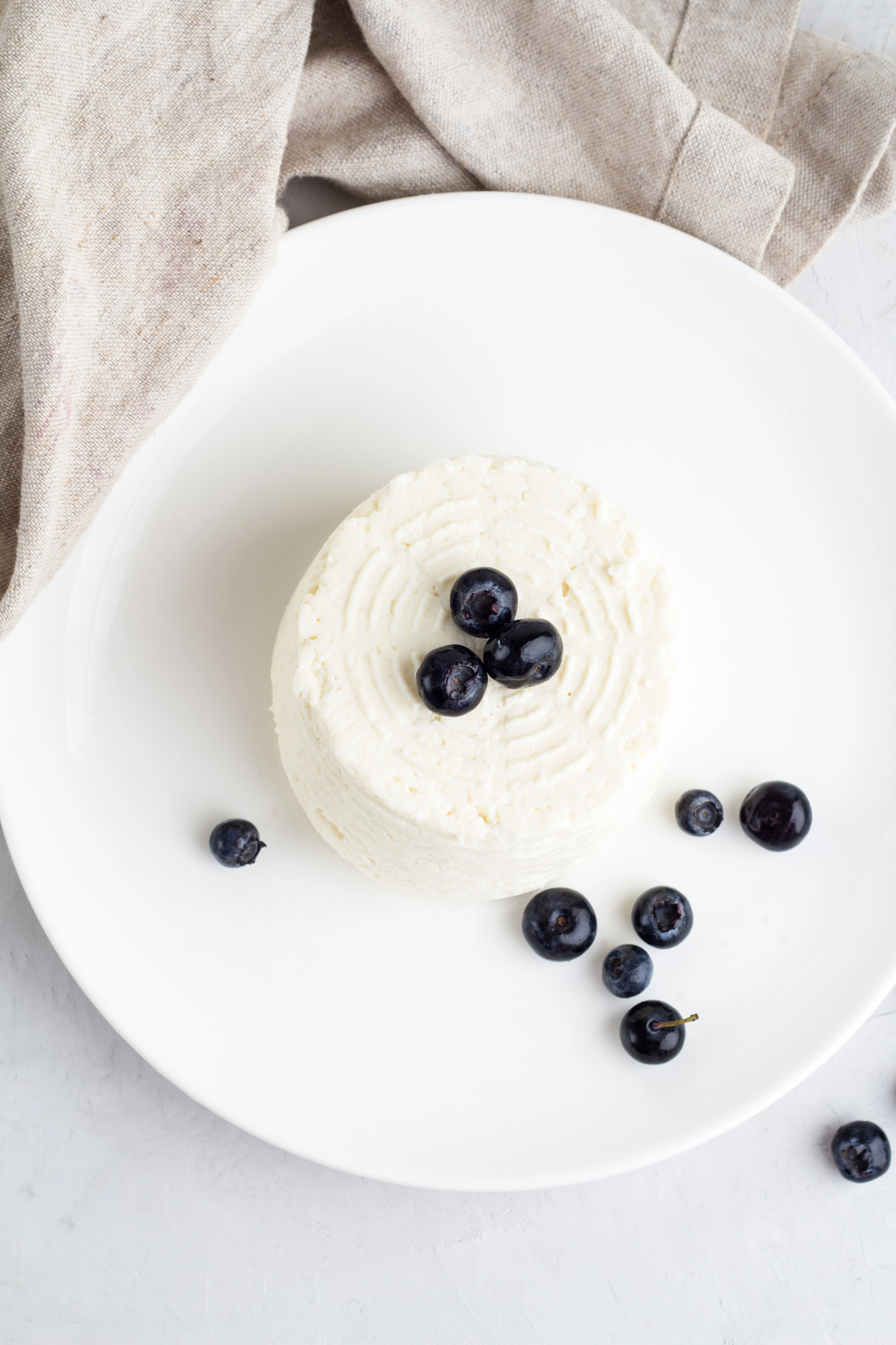 White ricotta dollop topped with blueberries on plate