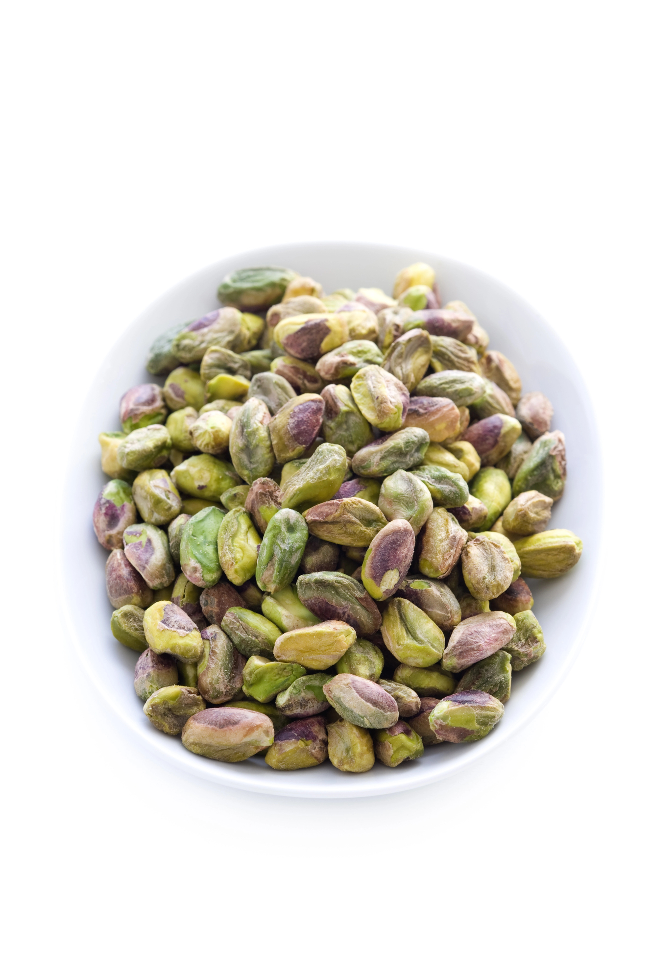 Whole shelled pistachio nuts in white bowl