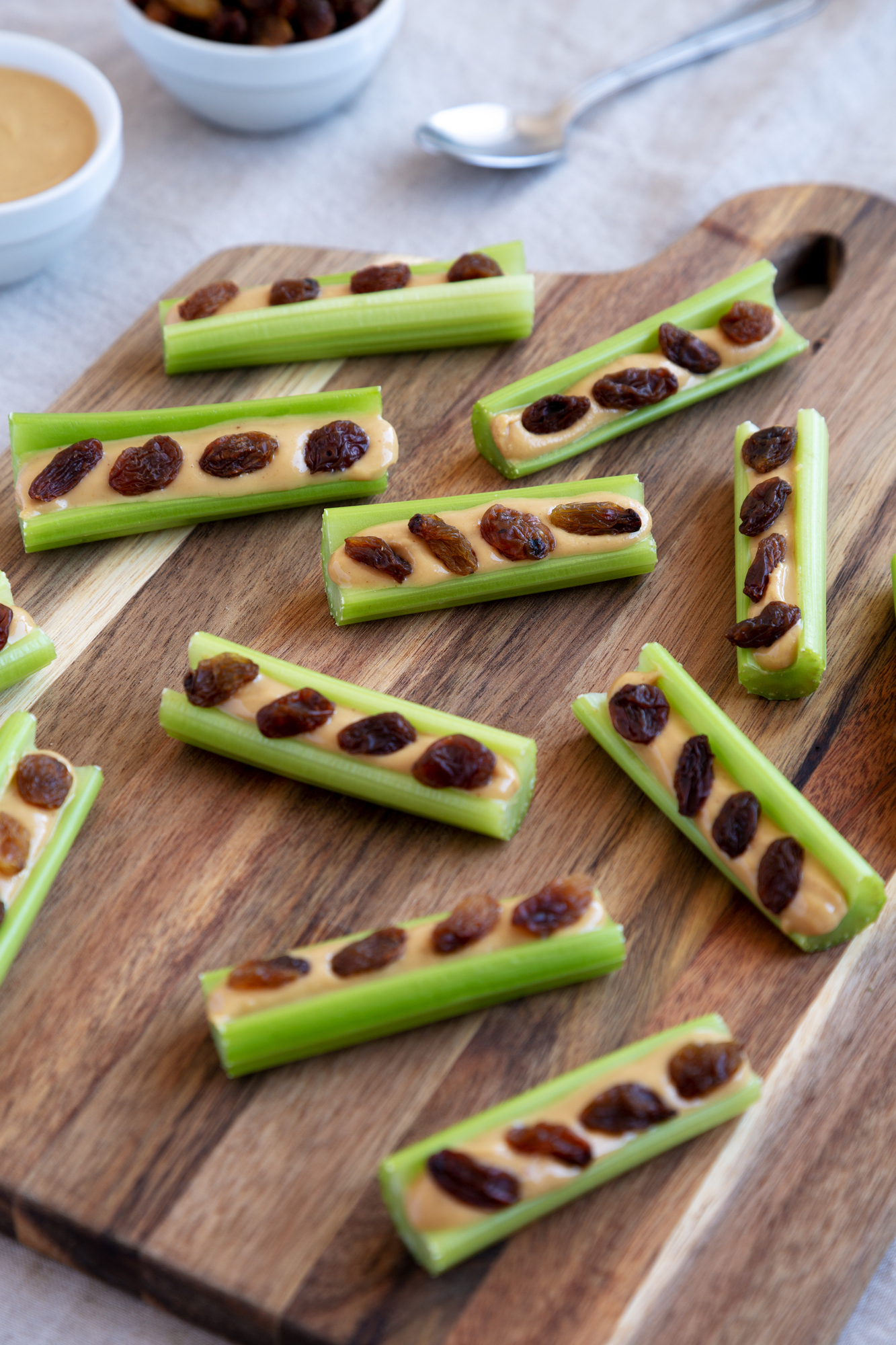 Celery sticks with peanut butter and raisins on wooden board