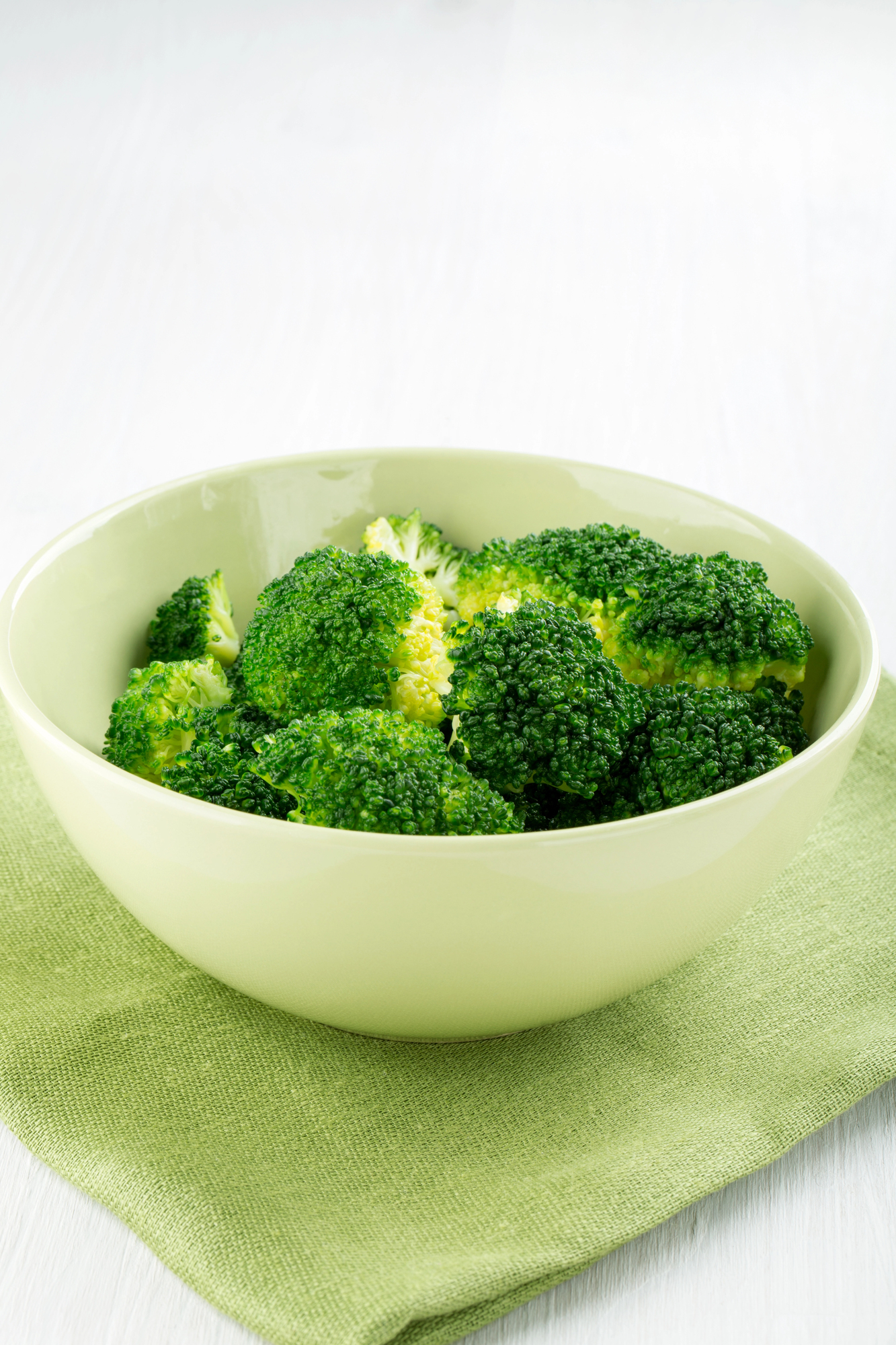 Boiled broccoli florets in a pale green bowl