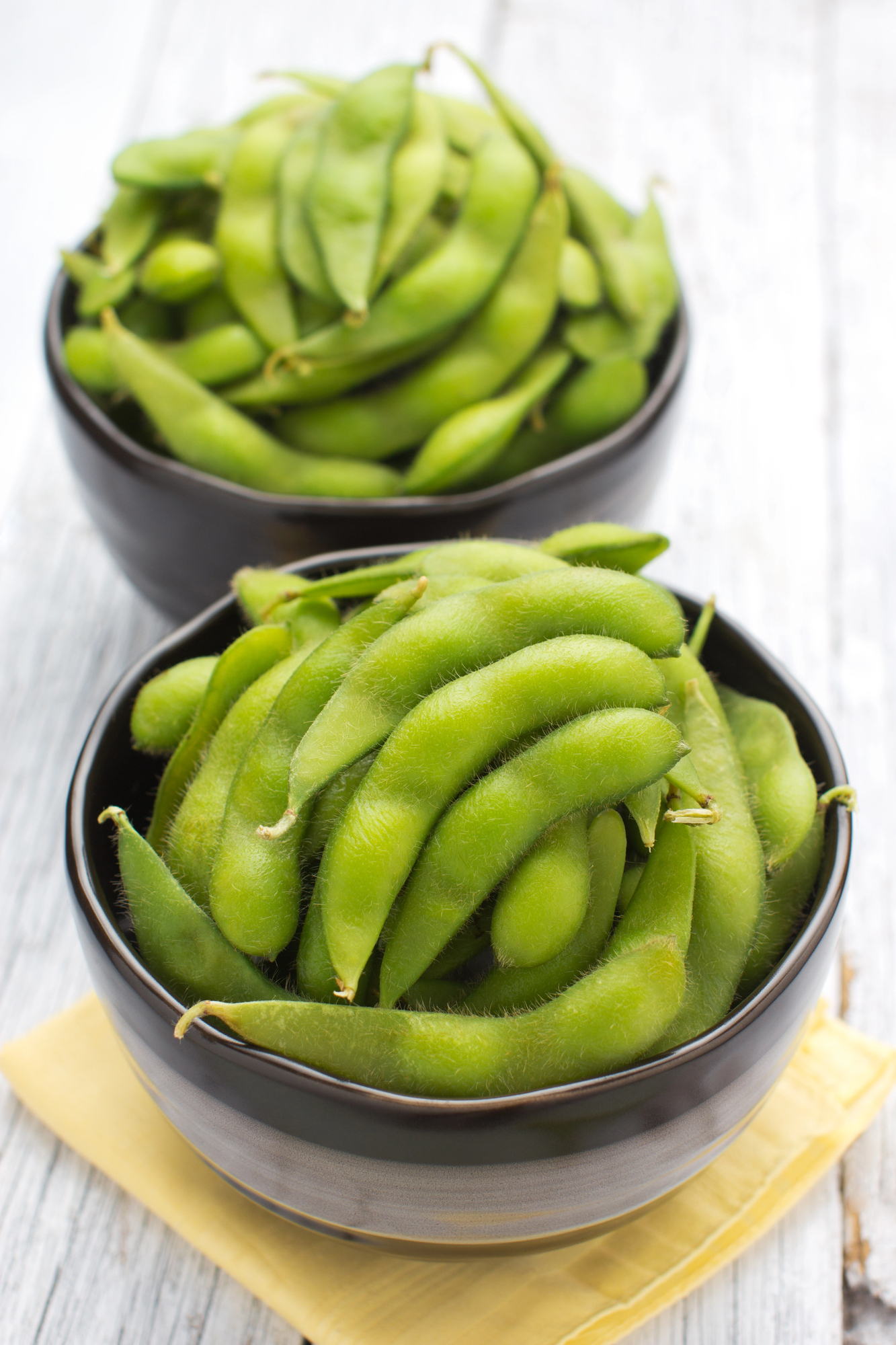 Fresh green edamame in two black bowls