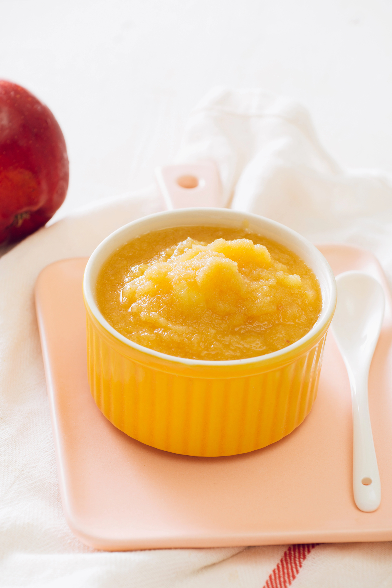 Yellow apple puree in ceramic bowl with spoon