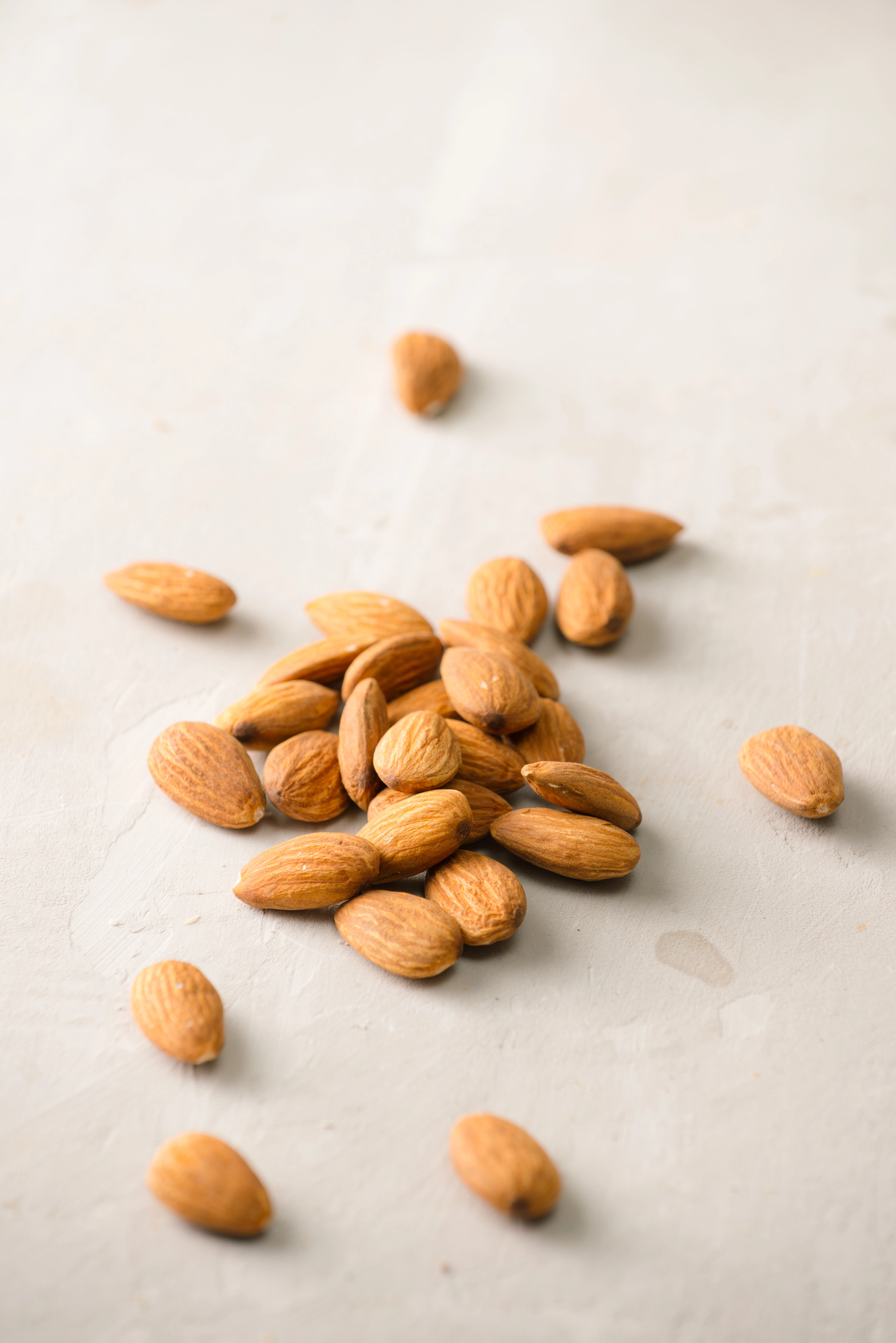 Pile of roasted almonds scattered on white surface