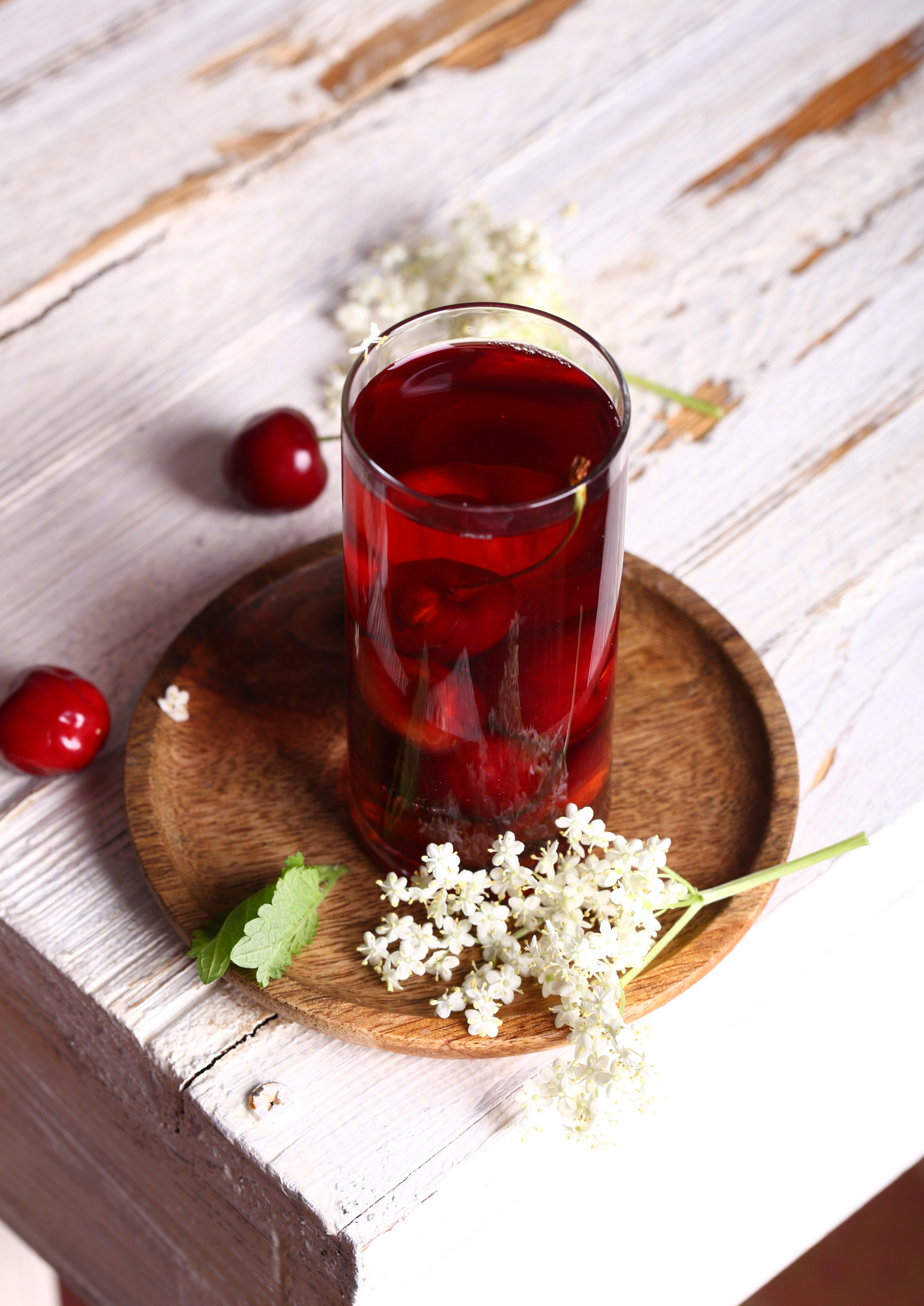 Glass of dark red cherry juice on wooden coaster