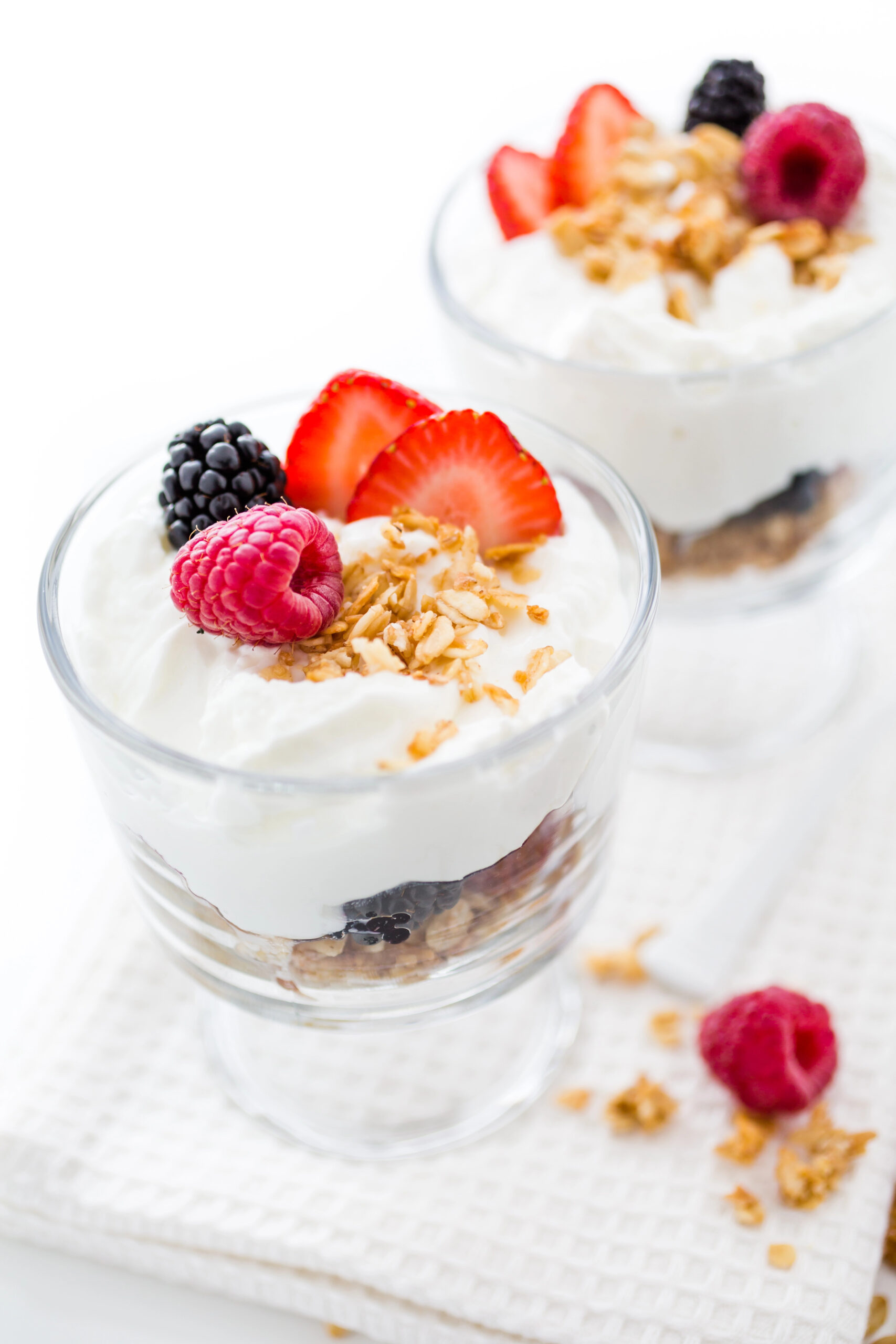 Two glass parfaits with yogurt berries and granola