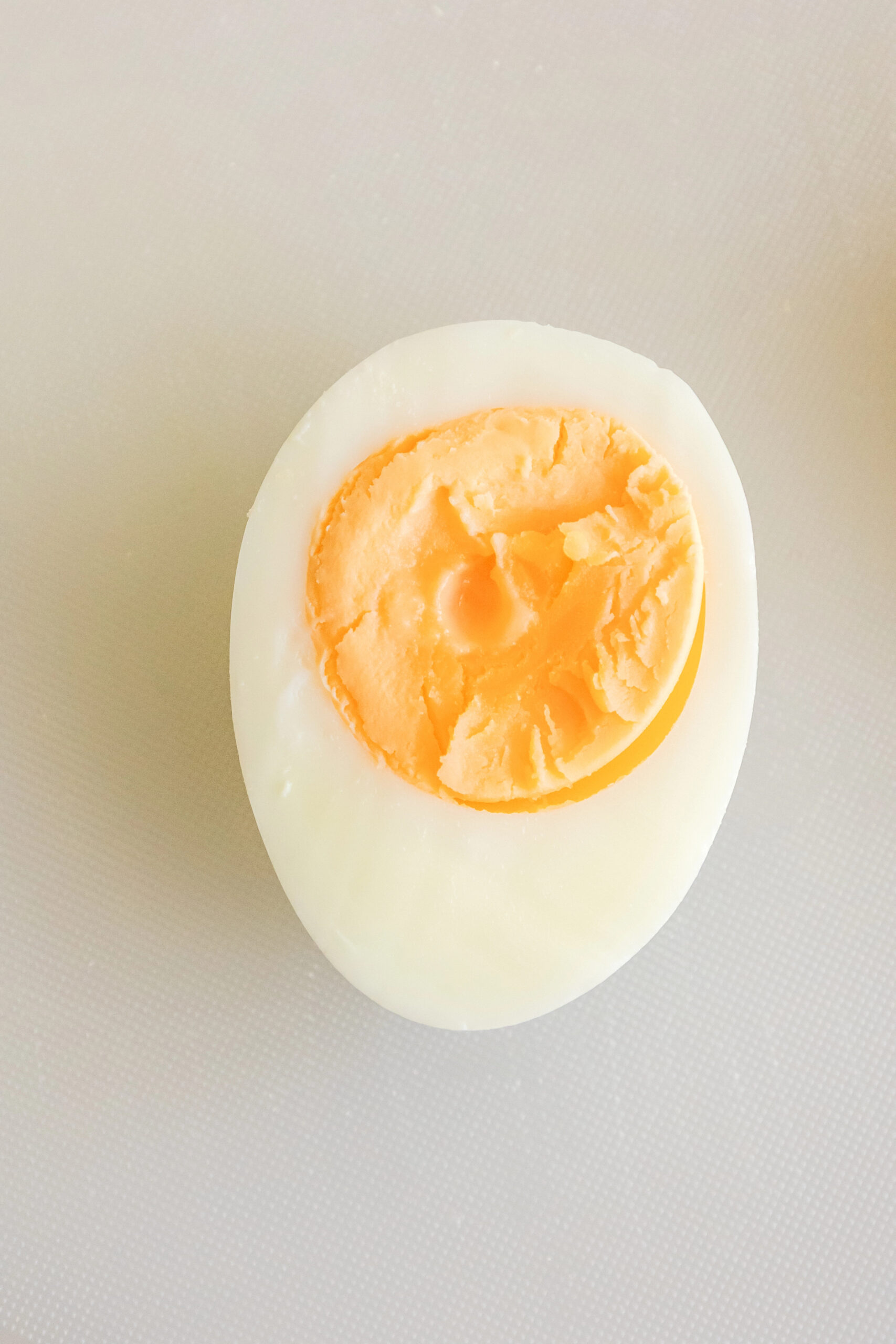 Hard boiled egg halved with orange slice on white