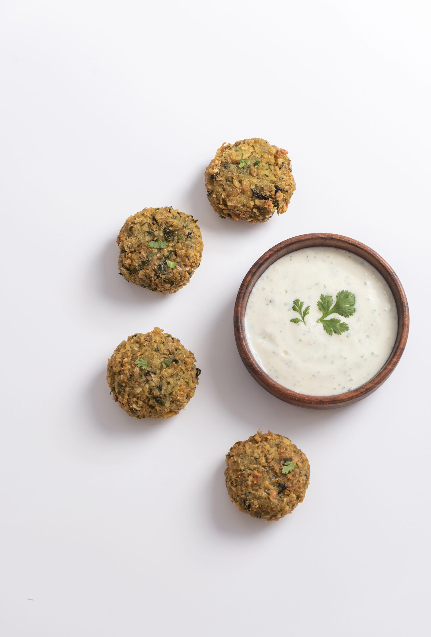 Four falafel balls and bowl of tzatziki sauce