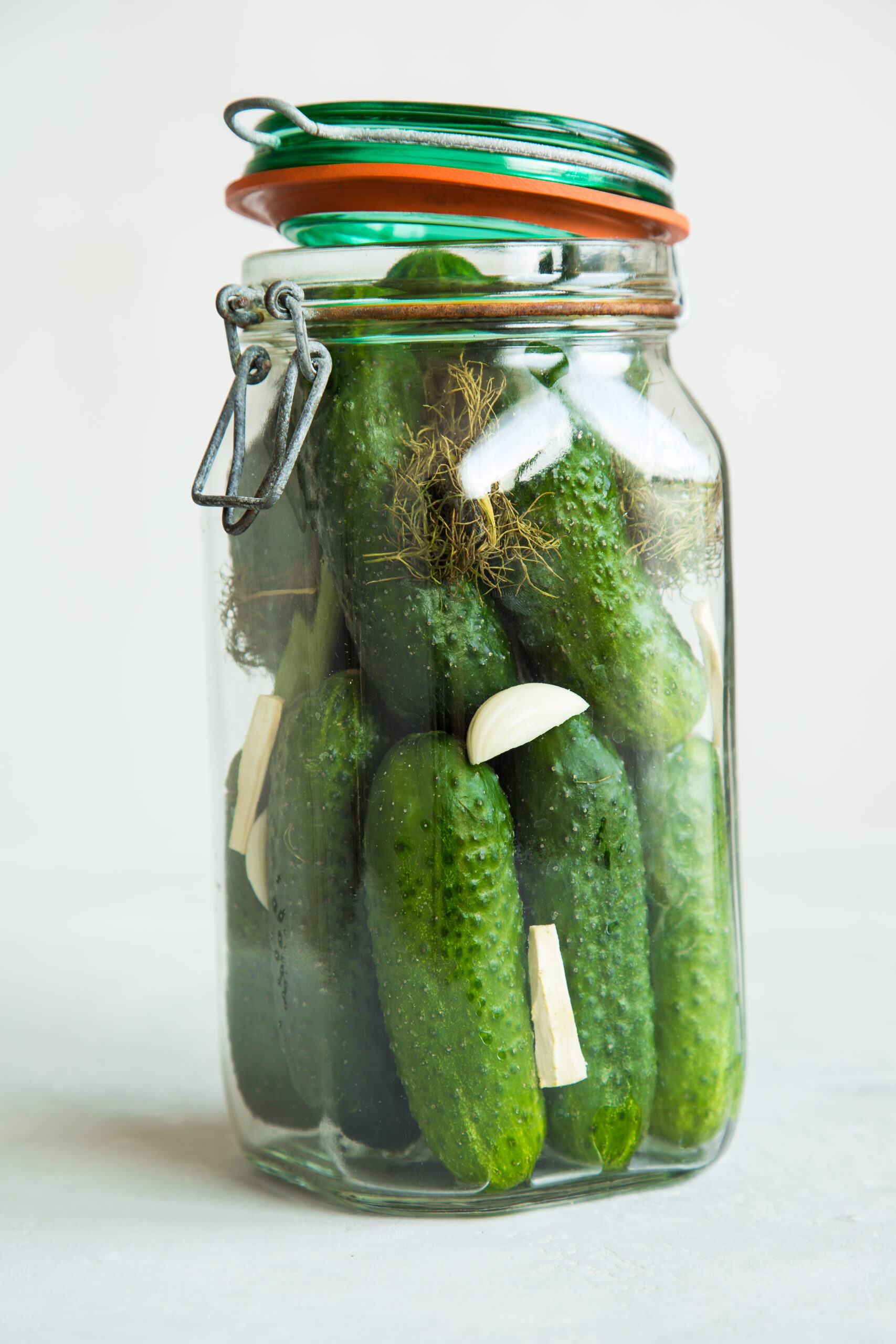 Pickled cucumbers in glass jar with garlic and dill