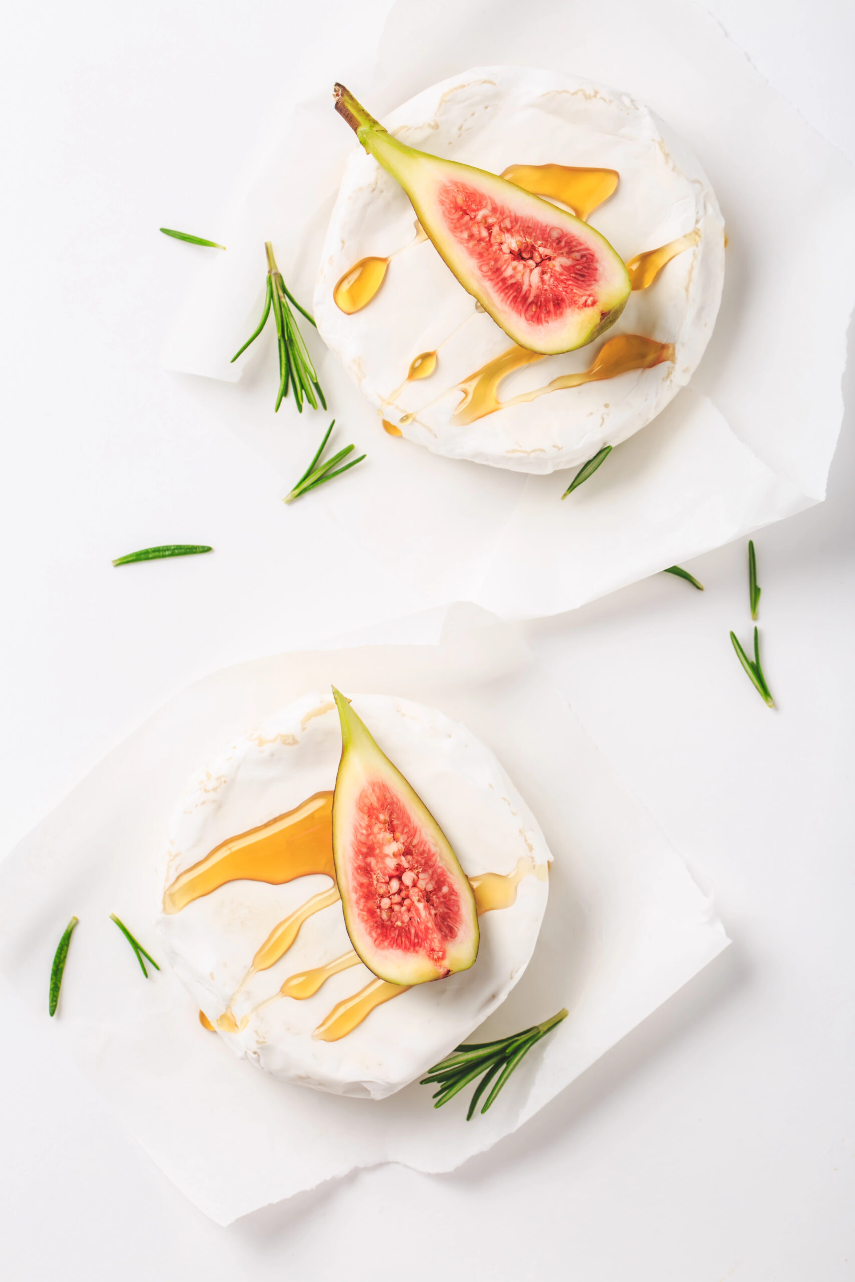 Two plates of camembert cheese with fresh figs and honey