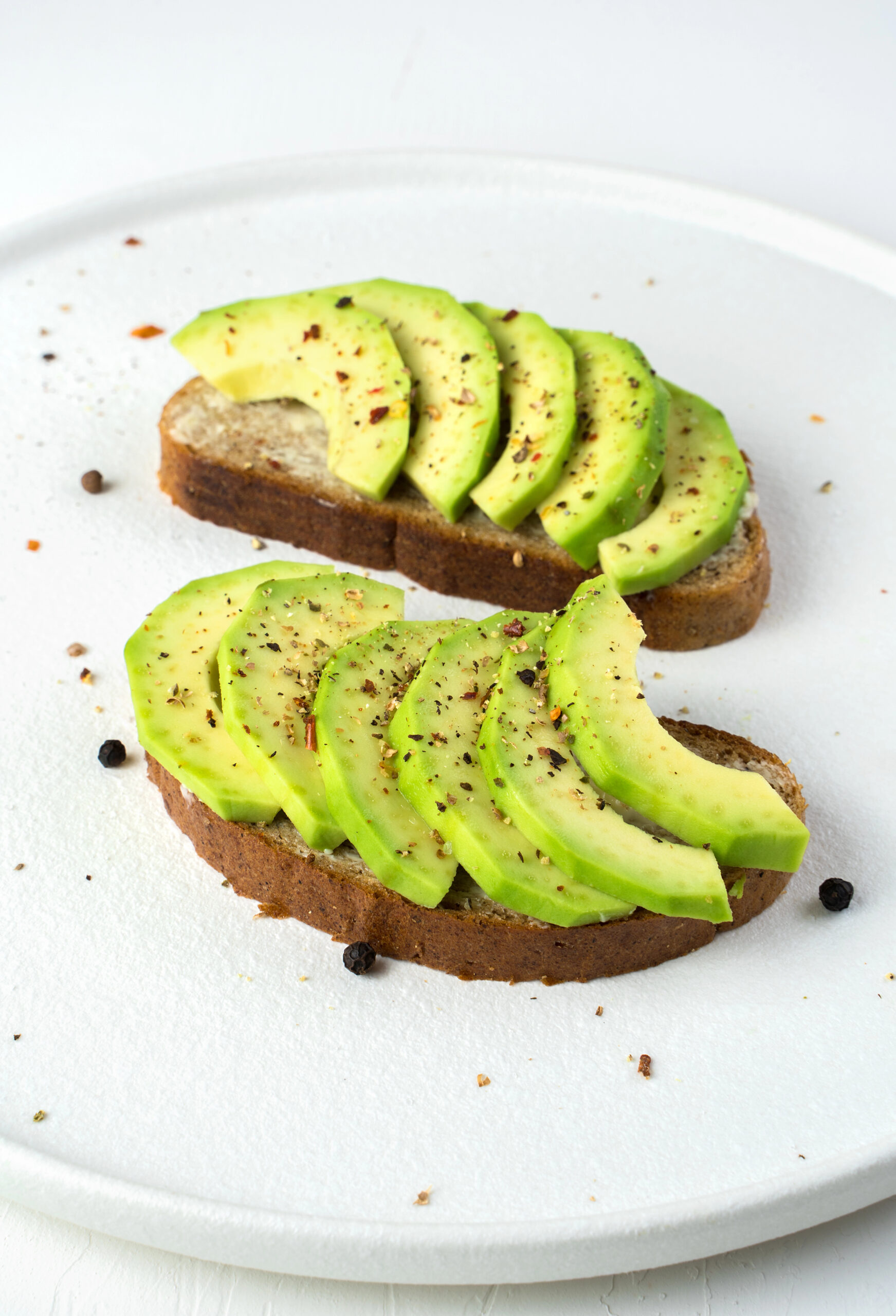 Two sliced avocado toasts on white plate