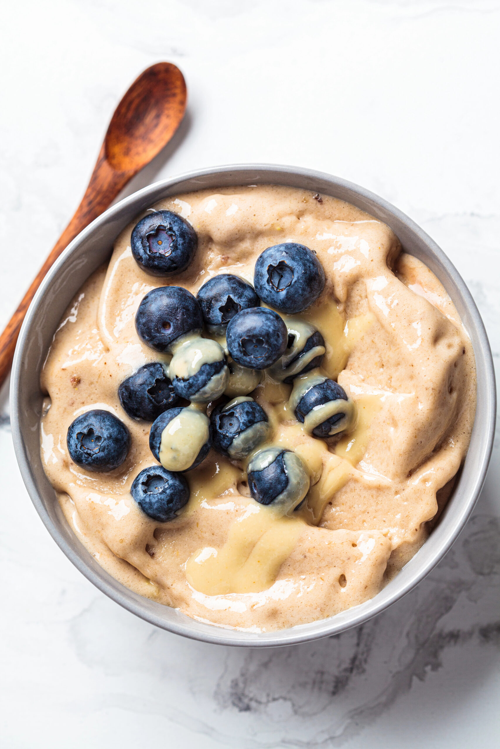 Banana ice cream topped with fresh blueberries in a bowl