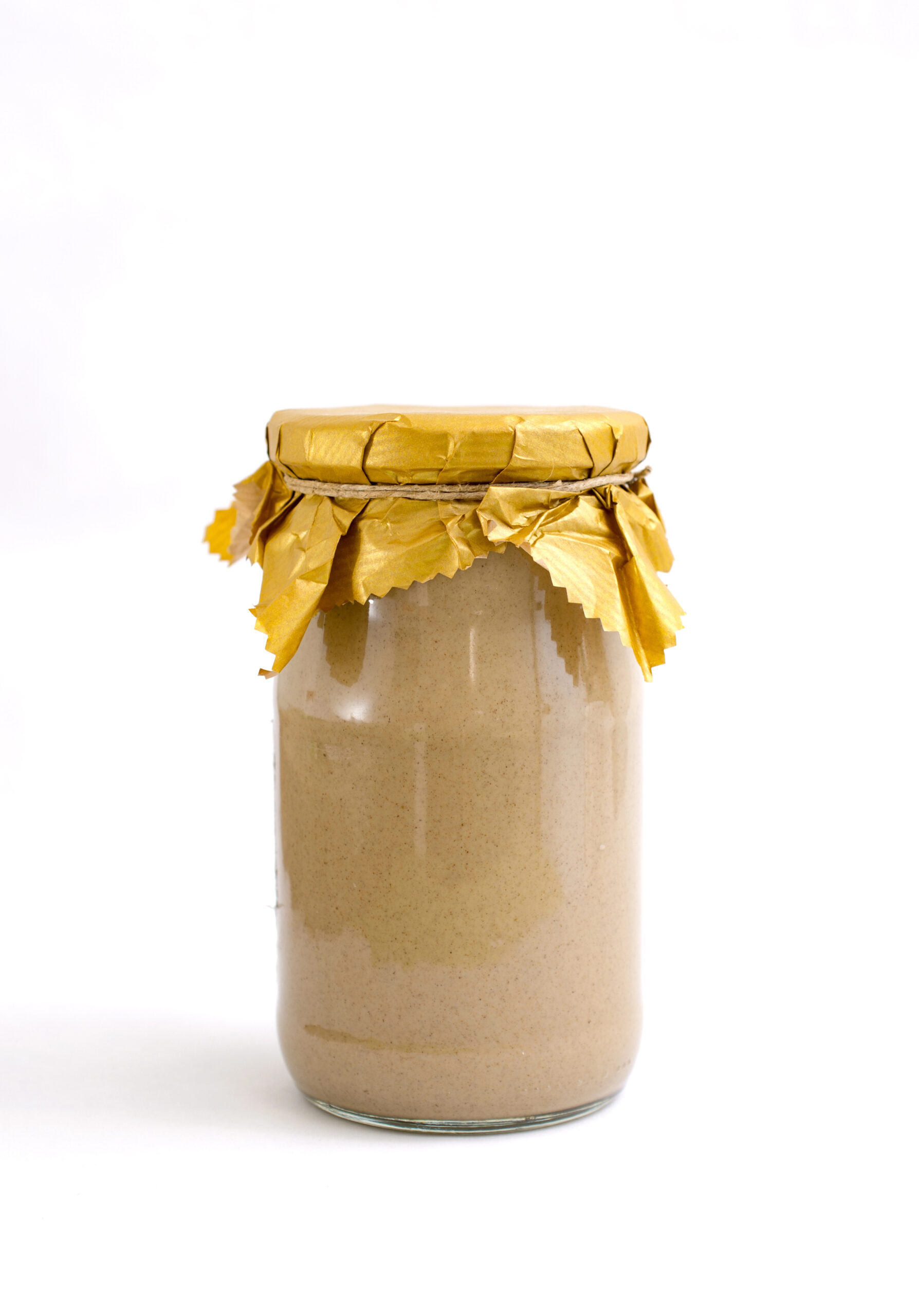 Tahini in a glass jar with gold cloth tie
