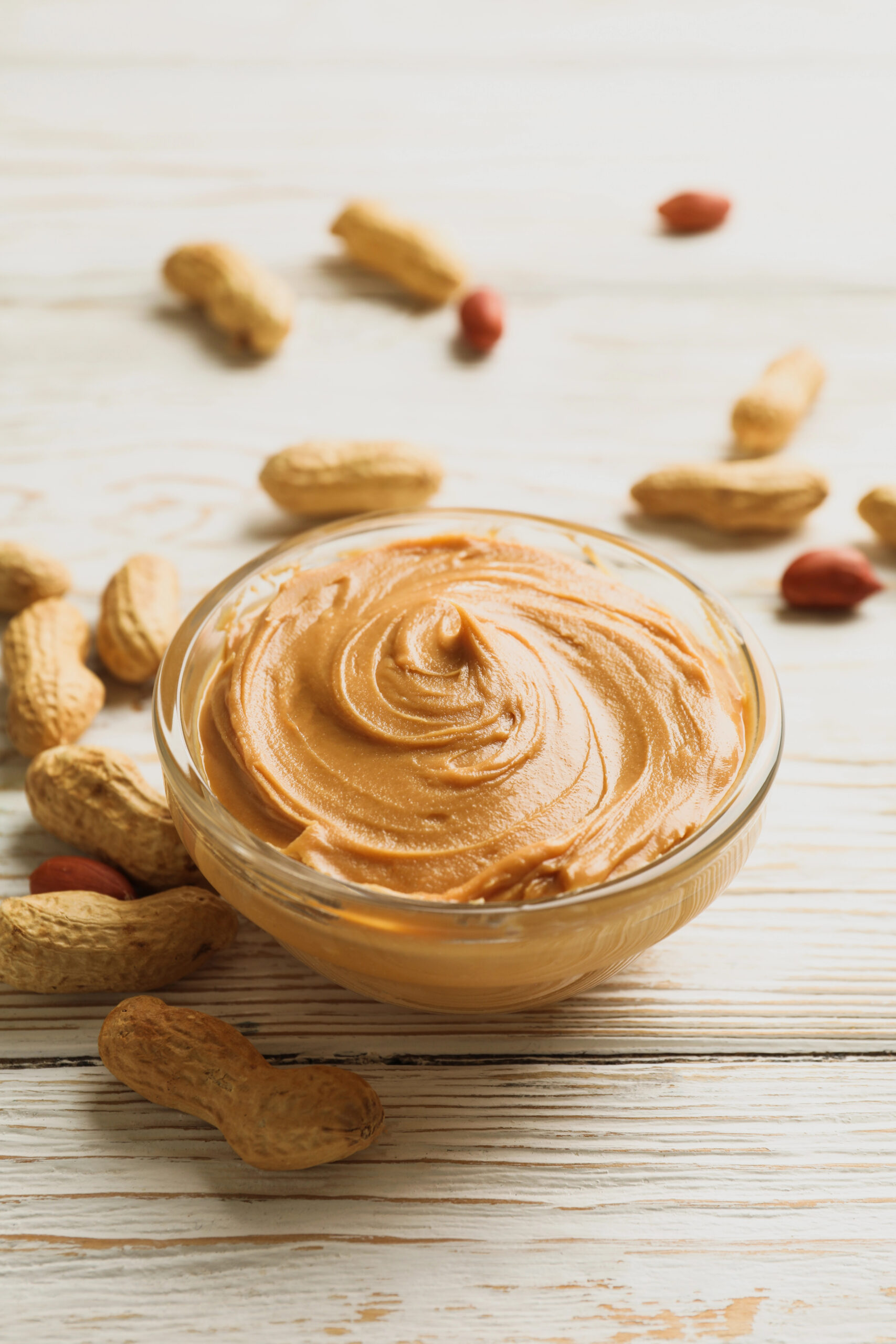 Bowl of peanut butter surrounded by peanuts