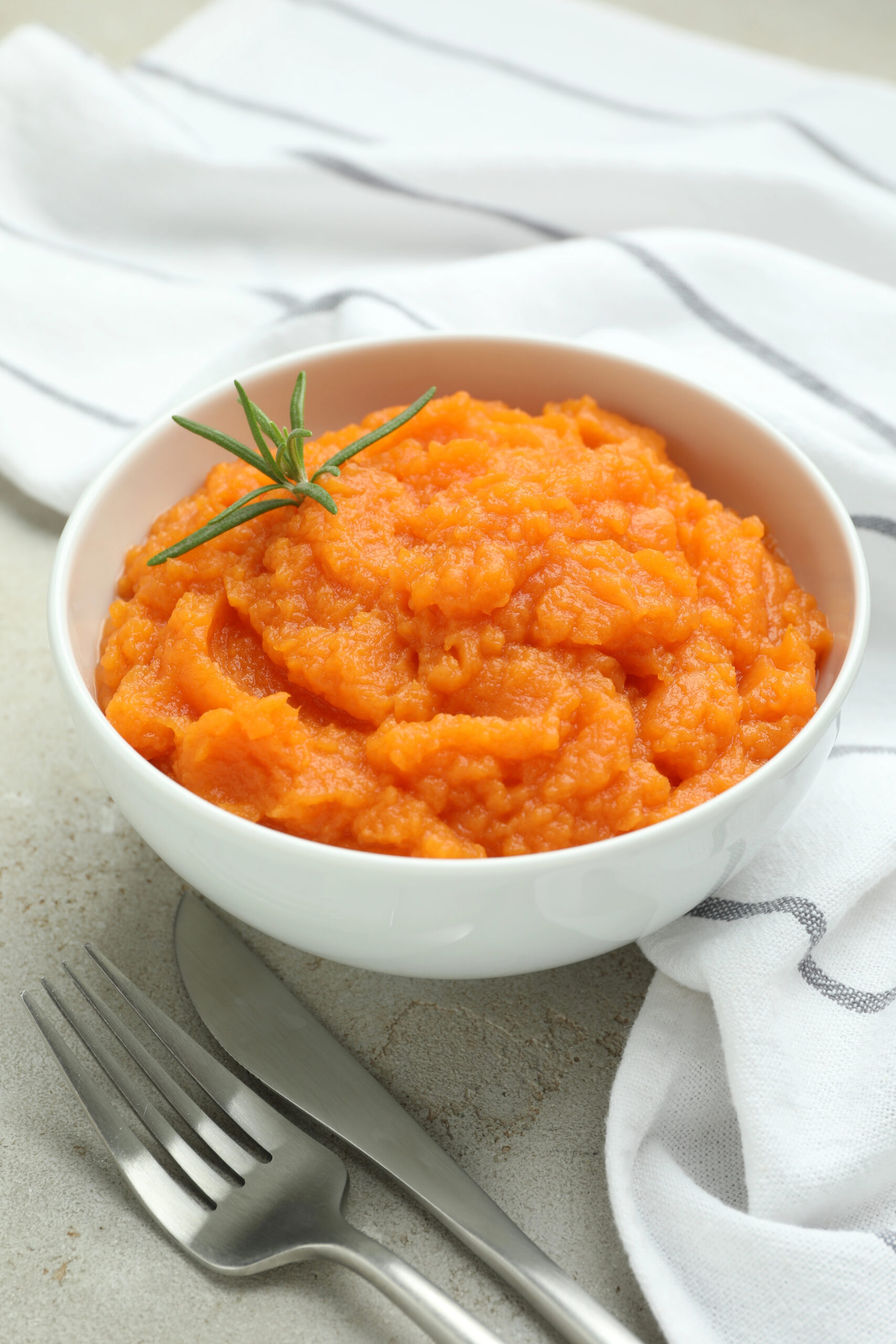 Mashed sweet potato and rosemary in white bowl