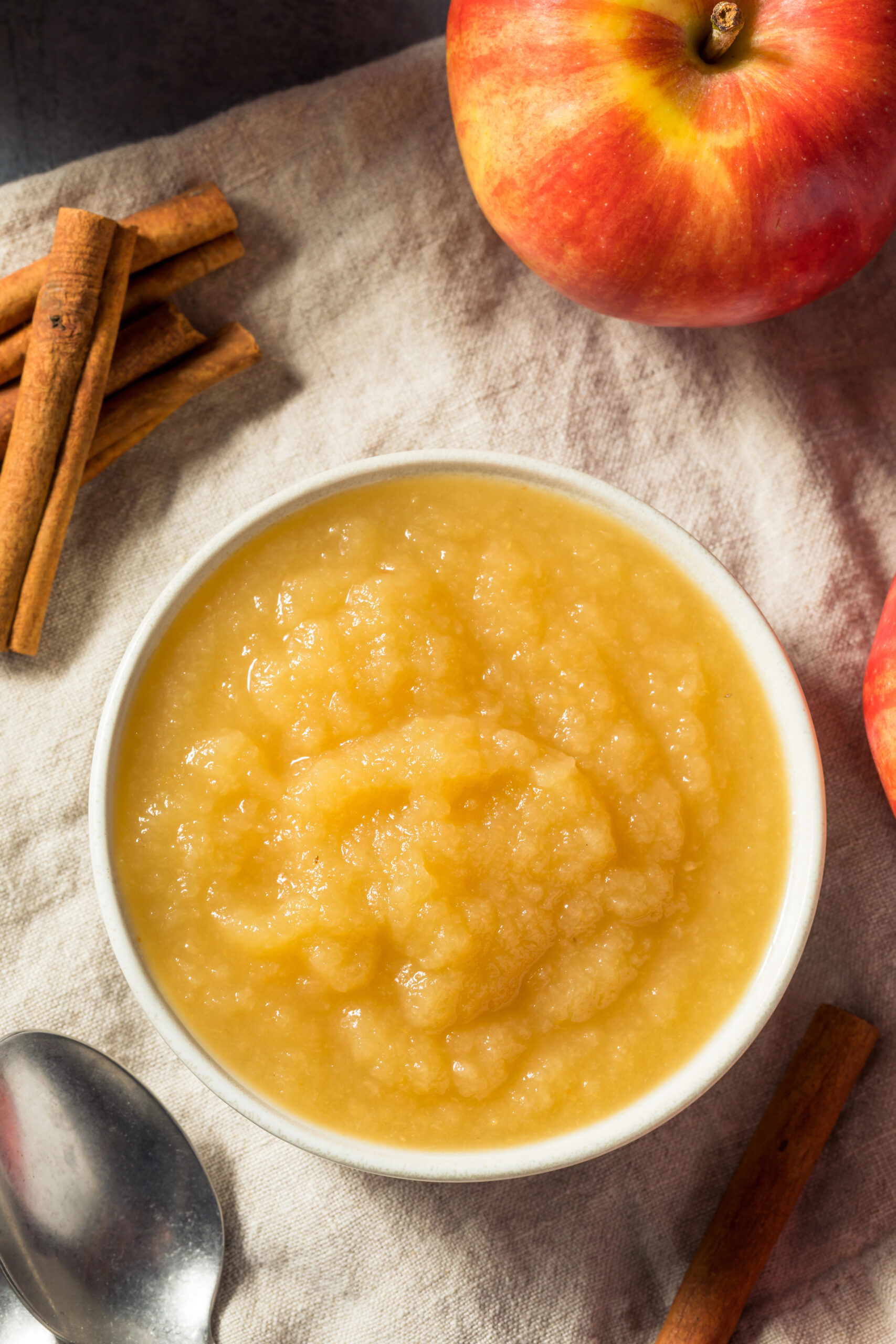 Bowl of applesauce with cinnamon sticks and apple