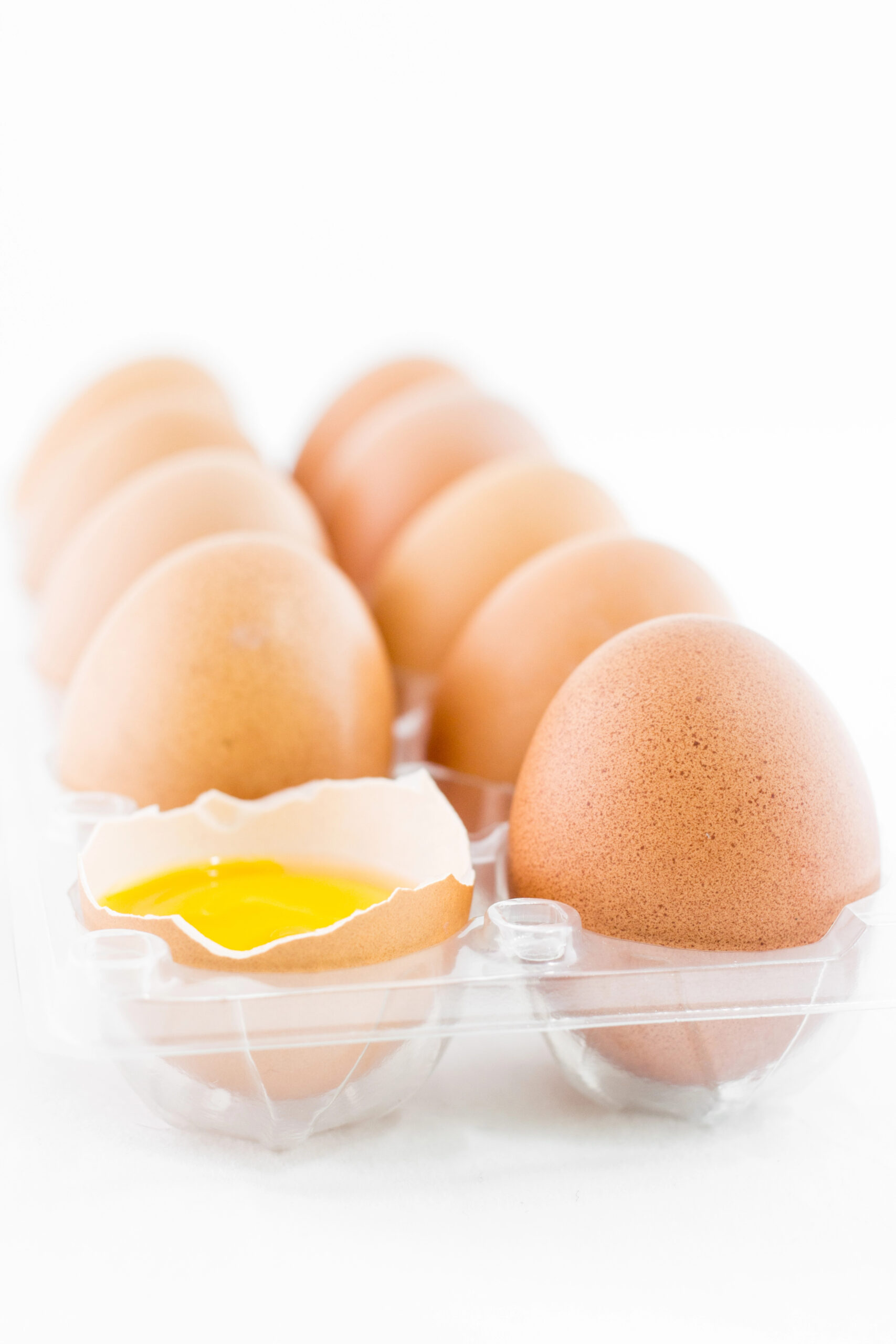 Brown eggs in clear carton with one cracked open