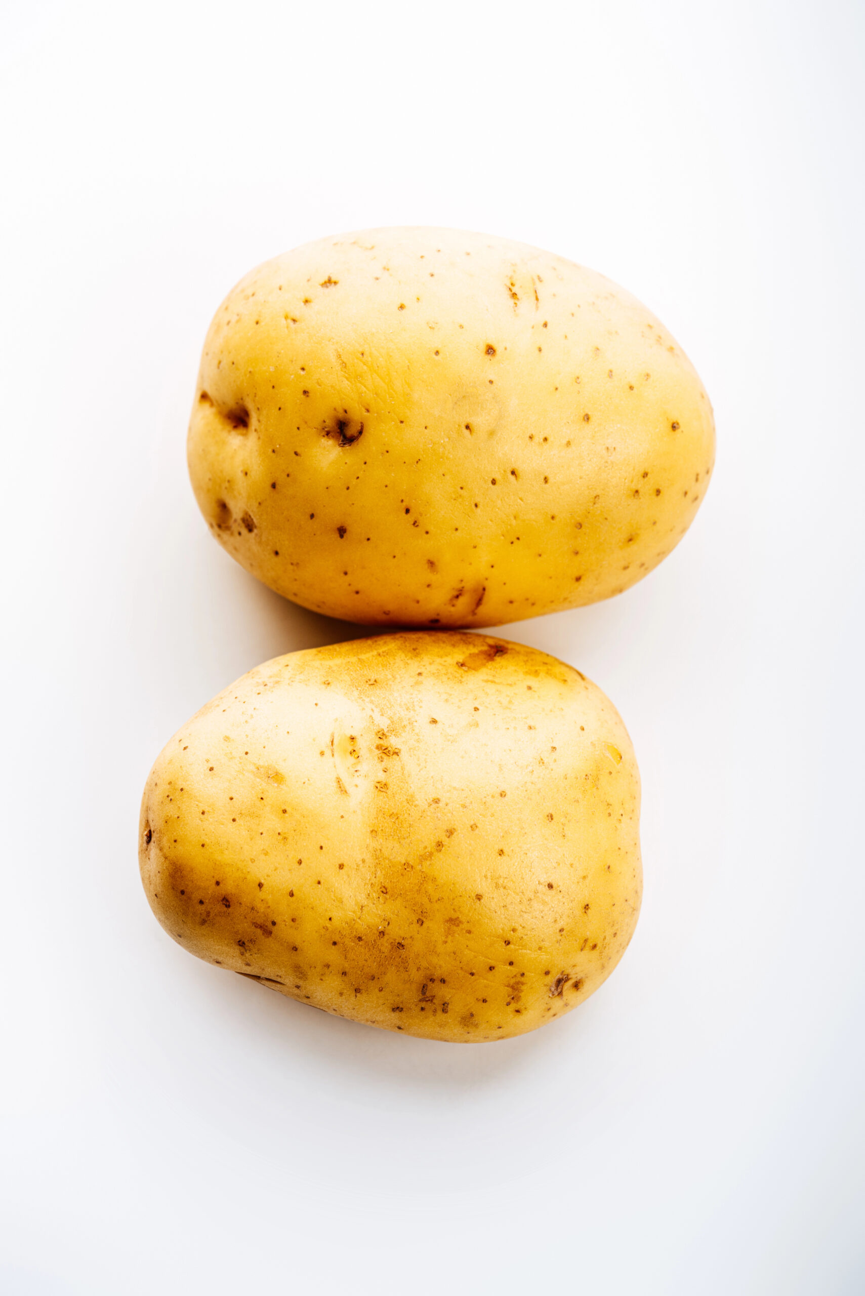Two whole raw potatoes stacked
