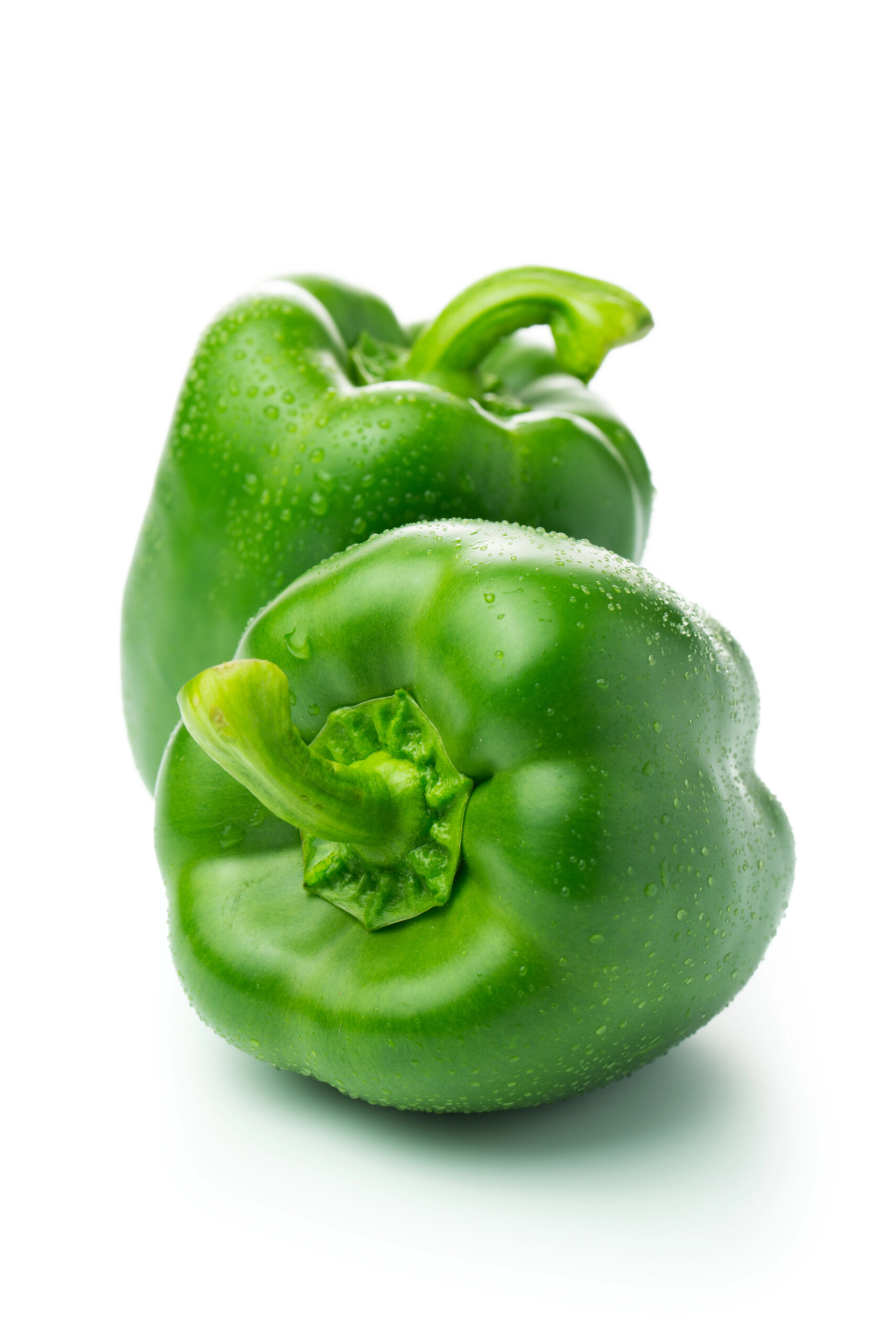 Two whole green bell peppers with water droplets