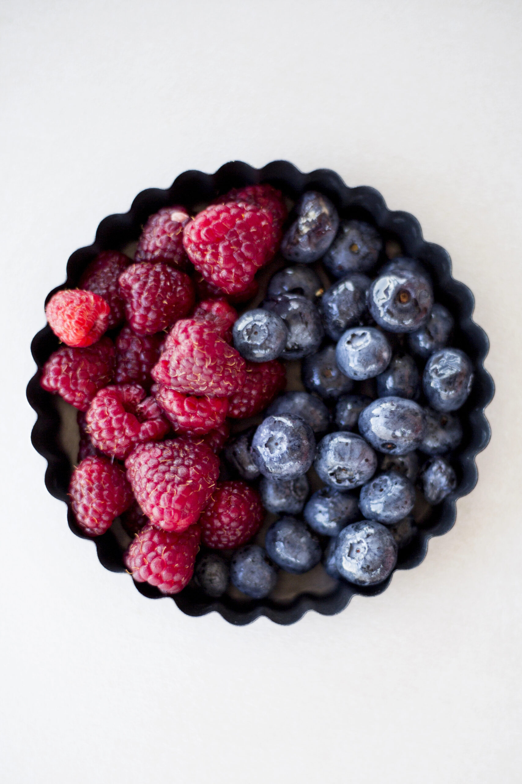 Raspberries and blueberries in black fluted tart shell