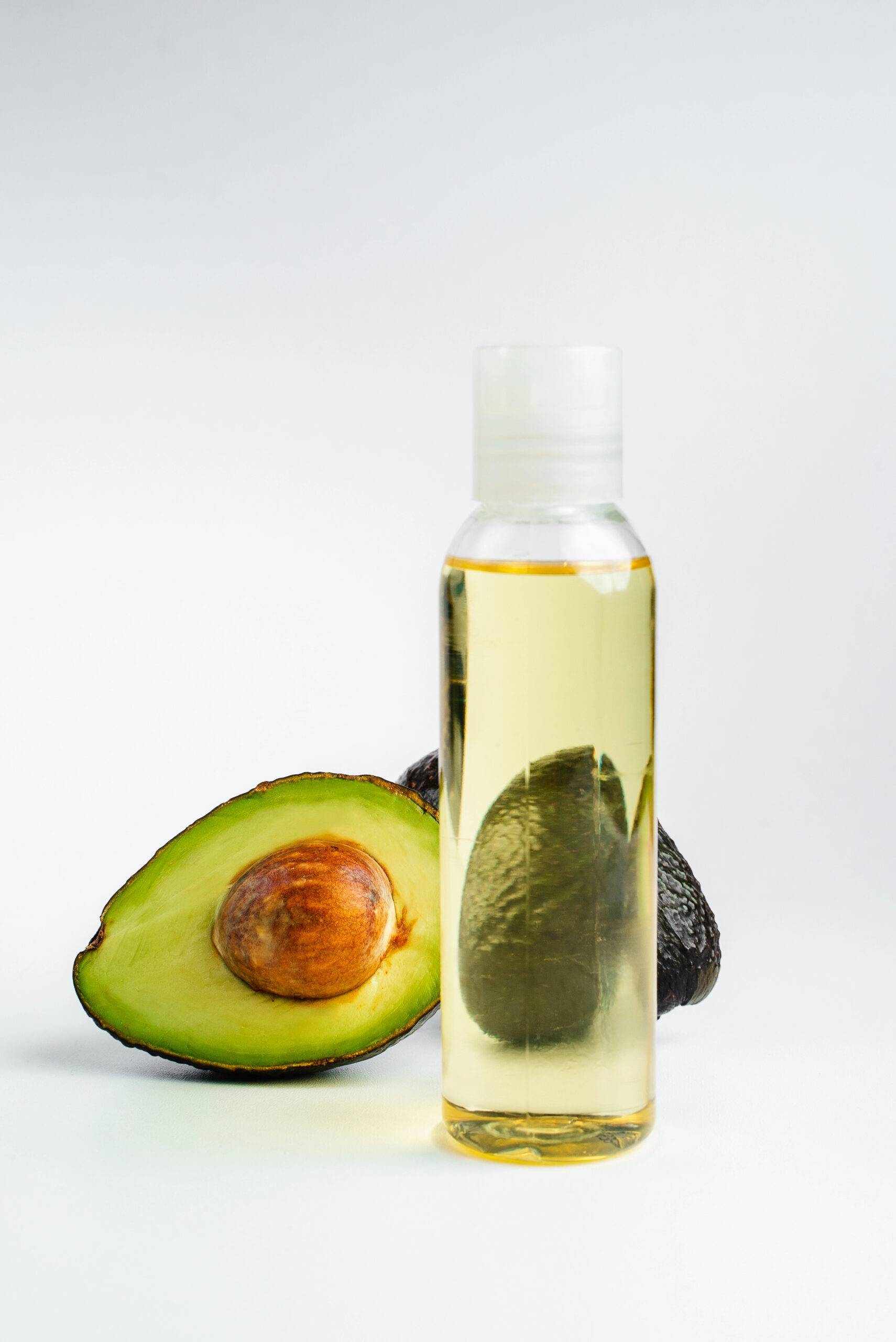 Bottle of avocado oil with fresh avocado halves