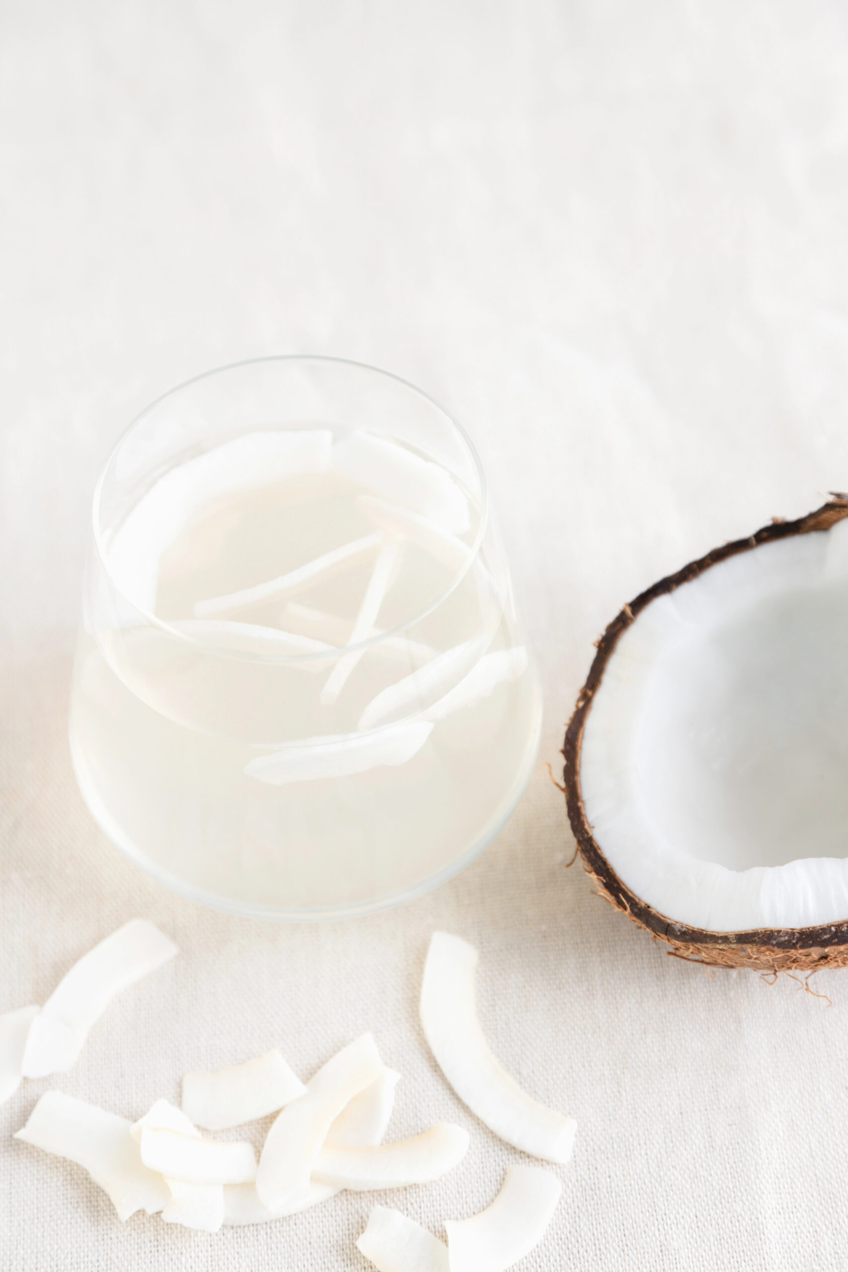 Glass of coconut water with coconut chips and half coconut