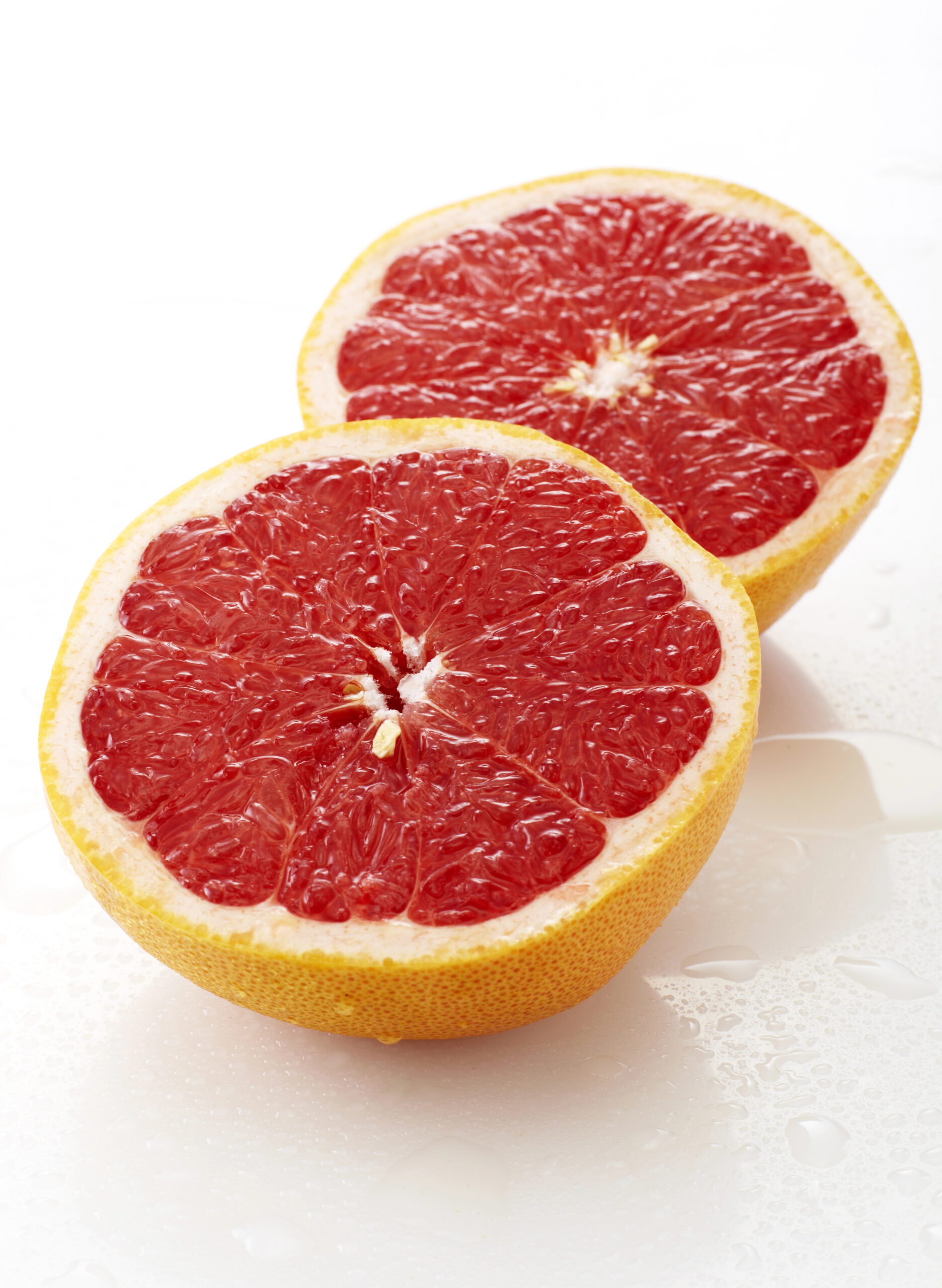 Two halved red grapefruit halves side by side
