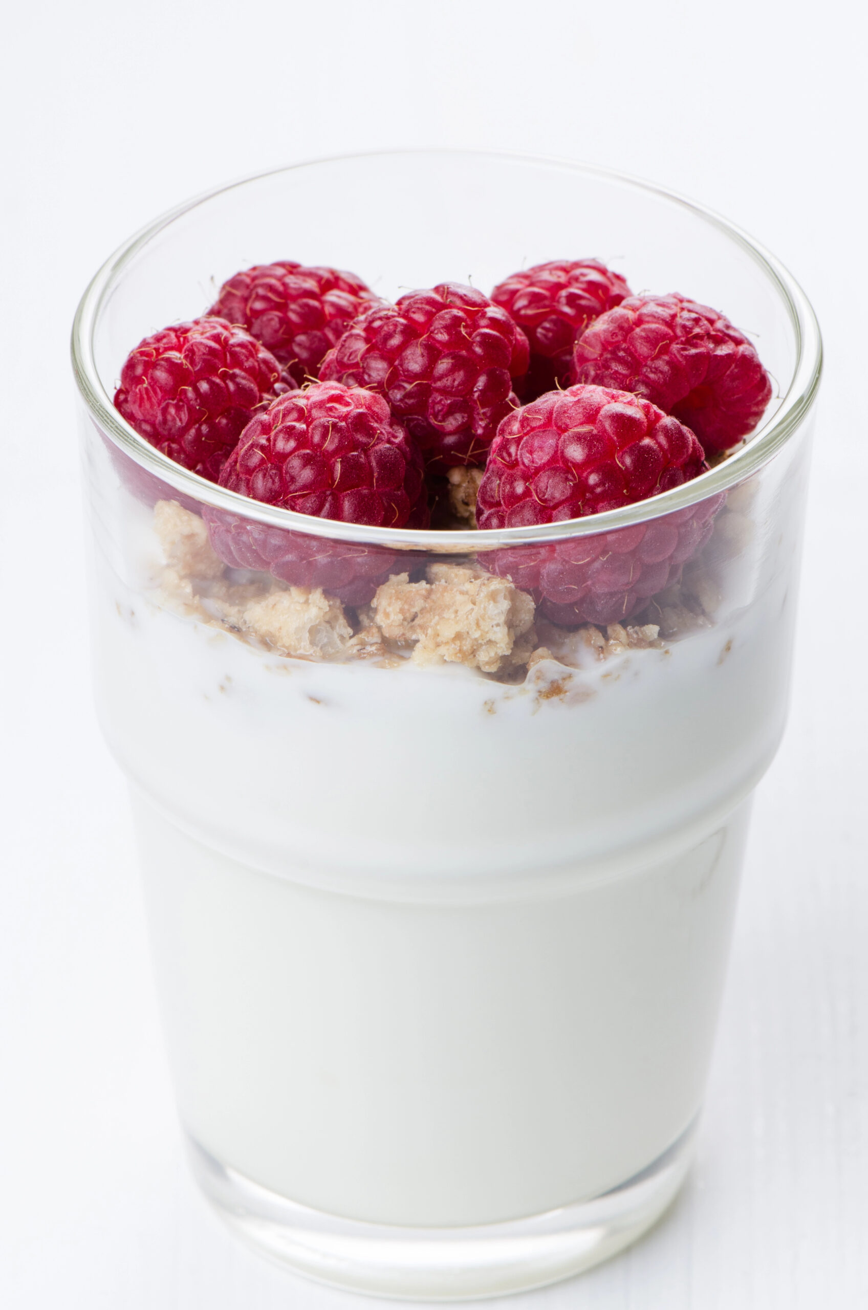 Yogurt with raspberries and granola in clear glass