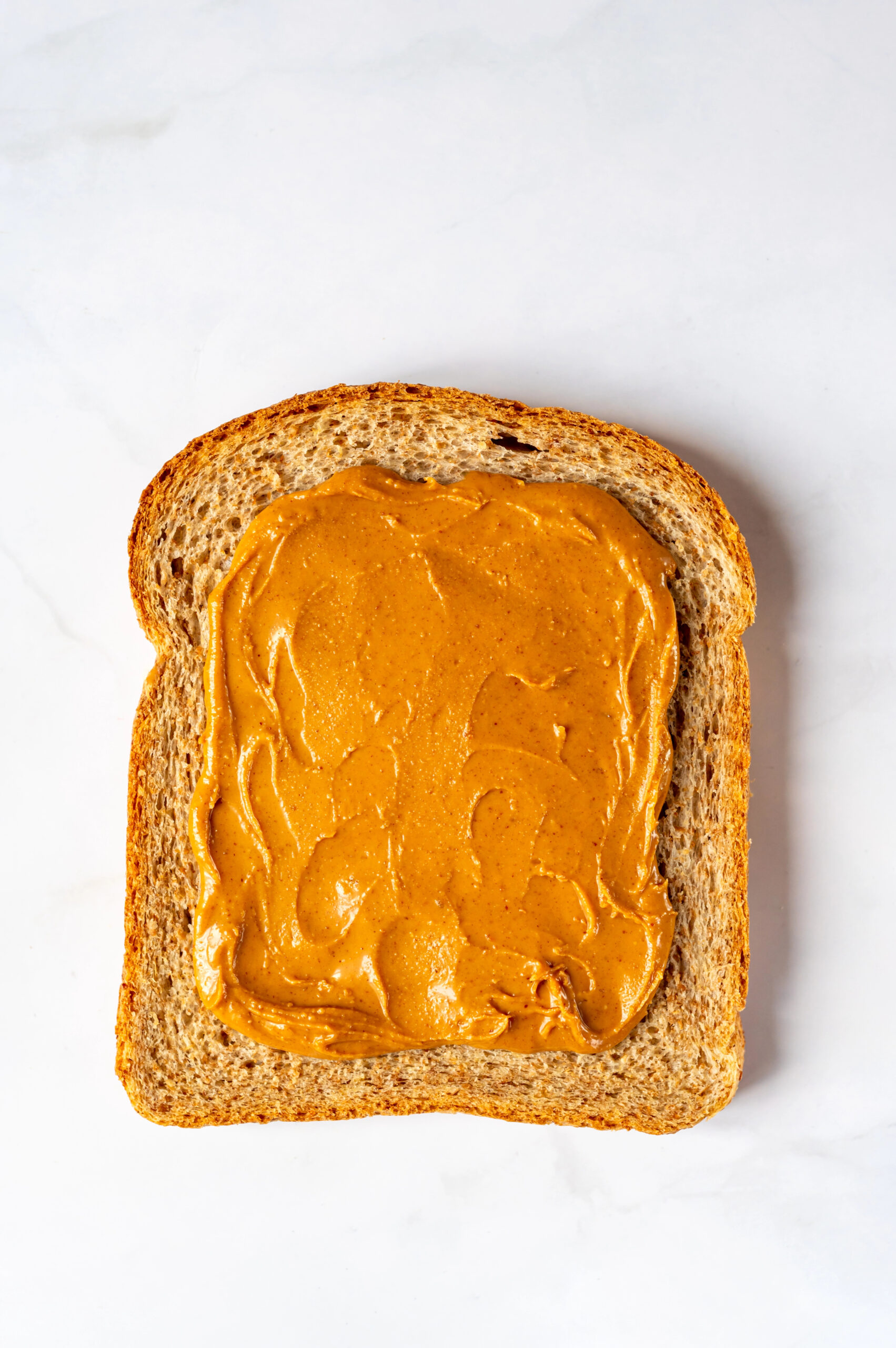 Slice of wholegrain bread spread with peanut butter